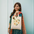 Woman holding a tote bag with floral embroidery against a light blue background