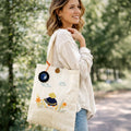Woman holding a tote bag with floral embroidery in a park setting
