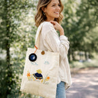 Woman holding a tote bag with floral embroidery in a park setting