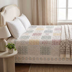 Lifestyle shot of applique cotton bedspread draped on a bed