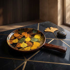 Elegant round mango wood serving tray with colorful autumn leaf enamel print on a luxury black marble table.