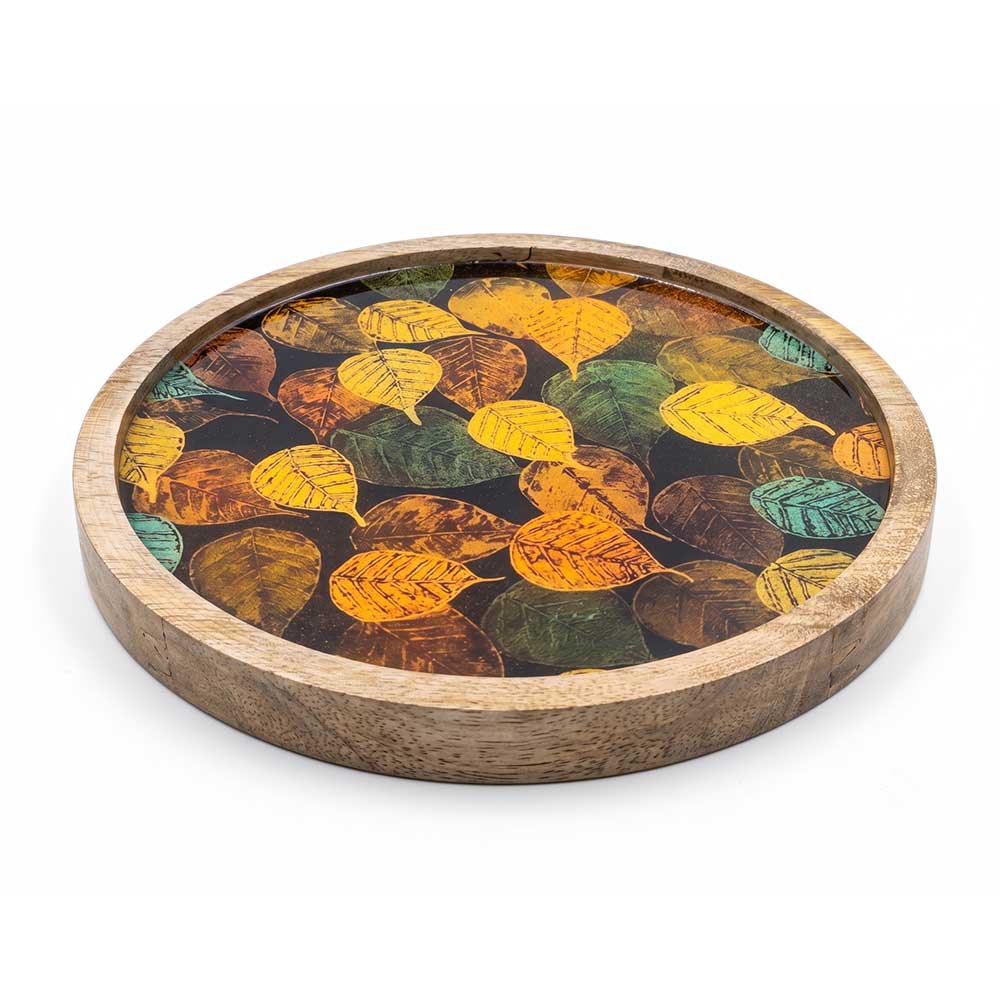 Detail view of the colorful enamel leaf print on the circular mango wood tray