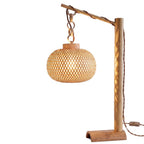 A rustic wooden table lamp with a curved arm, a vertical post, and a round woven rattan shade, shown against a plain white background.