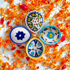 Close up detail view of hand-painted floral pattern on blue pottery diya