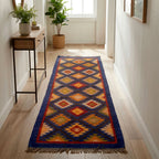 Colorful patterned rug on a wooden floor in a room with plants and a desk.