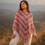 Outdoor lifestyle shot of a smiling woman wearing the hand-crocheted pink boho fringed poncho during golden hour