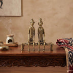 Two brass statues on a wooden table with a smoking incense burner in the background.