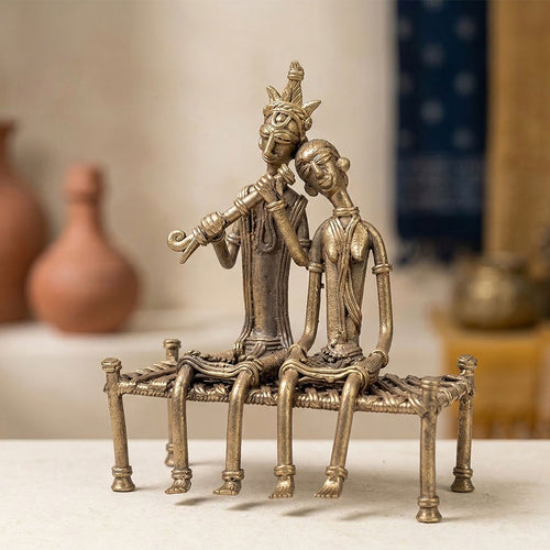 Bronze sculpture of two figures sitting on a bench with a blurred background