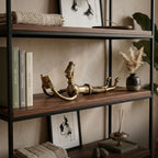 Decorative shelf with books, a gold sculpture, and a vase on a neutral background
