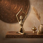 Bronze statue of a person in a yoga pose on a wooden platform with decorative elements.