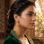 Close-up detail view of DI gold plated floral stud and filigree diamond motif with emerald green center stone