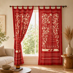 Red patterned curtains hanging in a living room with a window.