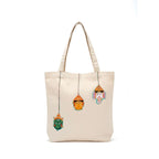 Beige tote bag with colorful deity face decorations on a white background