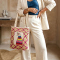 Person holding a colorful embroidered bag with a blurred indoor background