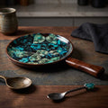A sleek, round mango wood serving tray featuring a vibrant blue and black leaf-patterned enamel surface, shown from a slightly elevated angle on a rustic wooden table.