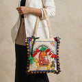 Handbag with intricate design and colorful patterns held by a person against a neutral background