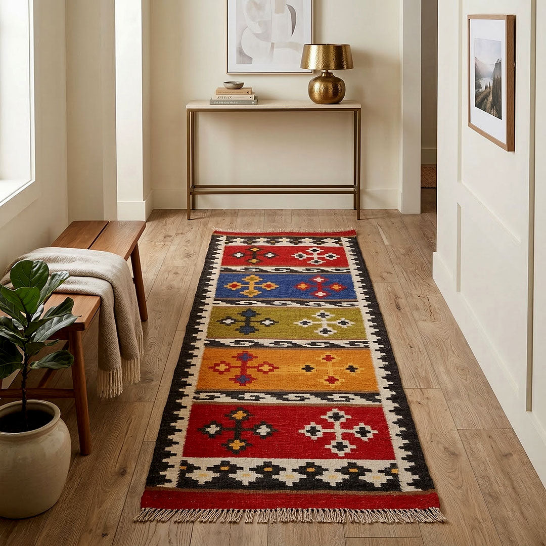 Colorful patterned rug on a wooden floor with a side table and lamp in the background.
