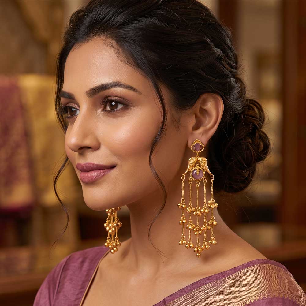 Detail view of the intricate bird motif and pink stone setting on gold-plated Jhumka earrings.