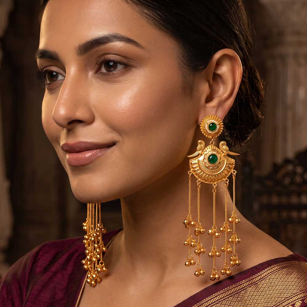 Close-up of traditional gold plated peacock jhumka earring craftsmanship with green stone detail