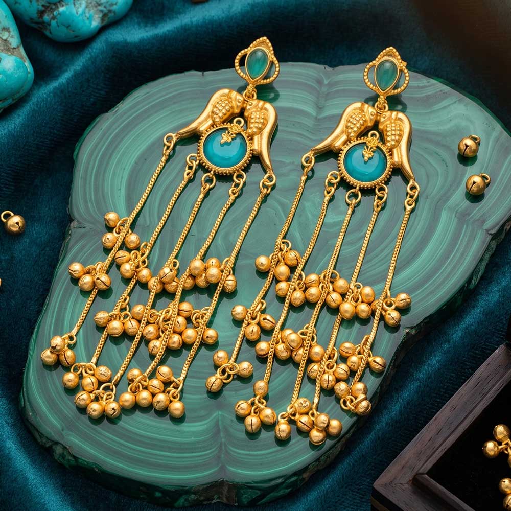 Macro detail shot of the turquoise stone and gold bird motif on the jhumka earrings.