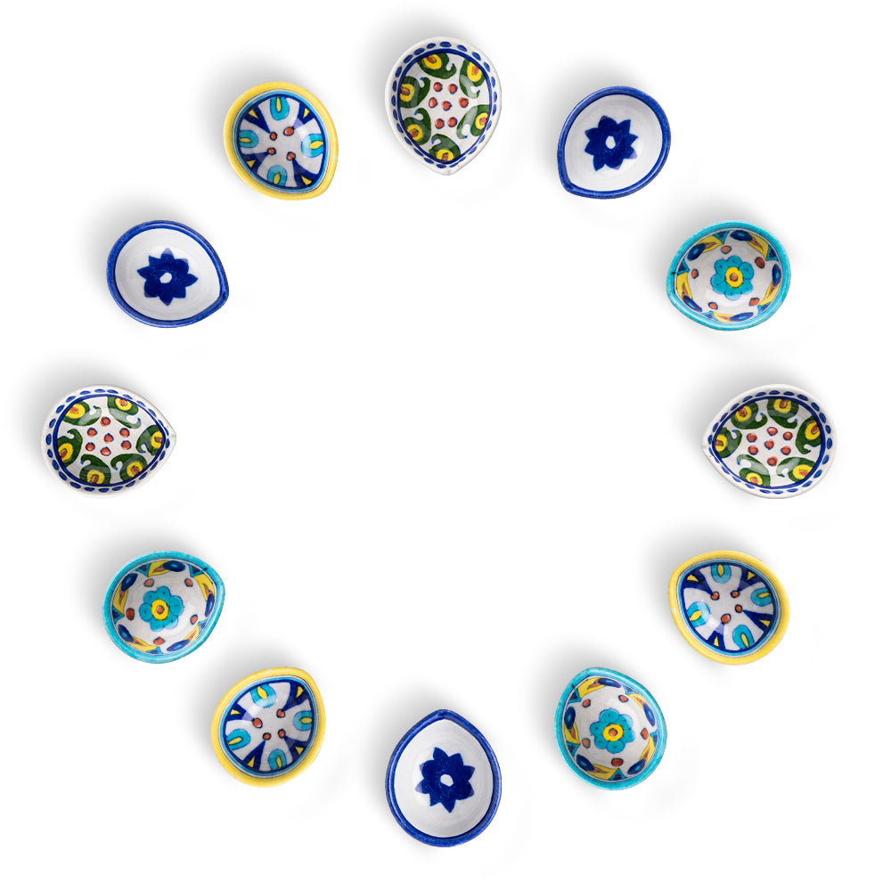 Set of 10 assorted hand-painted blue pottery diyas arranged in a circular formation on a white background.