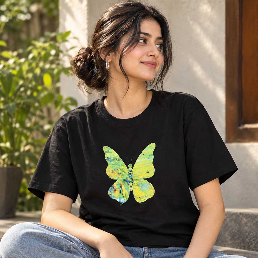 Close-up detail of the hand-painted yellow and green butterfly artwork on the black cotton t-shirt.
