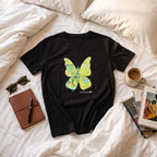 Full length view of the black hand-painted butterfly t-shirt on a clothes hanger against a neutral background.