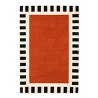 A luxurious hand-tufted New Zealand wool rug featuring a deep burnt-orange center and a black-and-cream striped border, viewed from a top-down flat perspective.