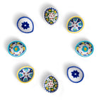 A top-down view of an assorted set of eight handcrafted blue pottery diyas featuring floral and geometric designs on a white background.
