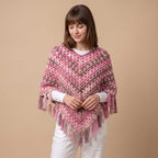 Model in studio wearing handmade pink and taupe crochet poncho over a white long-sleeve shirt