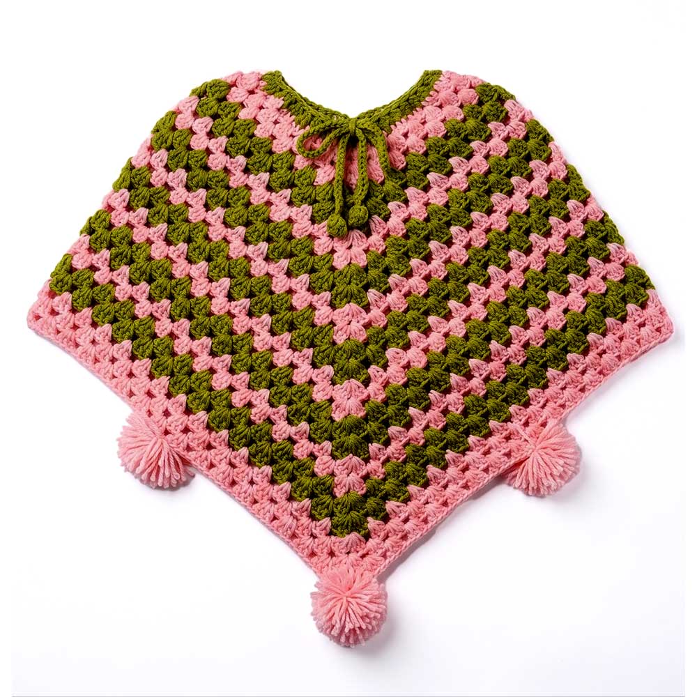 Handmade pink and olive green crochet poncho flat lay view with pom-poms and tie neckline