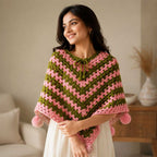 Model wearing the handcrafted olive green and pink crochet poncho with pom-poms