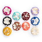 Assortment of handmade crochet ruffle hair scrunchies in various colorful contrast trim options on white background