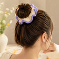 Model wearing cream and lavender crochet ruffle scrunchie styled around a high hair bun from behind