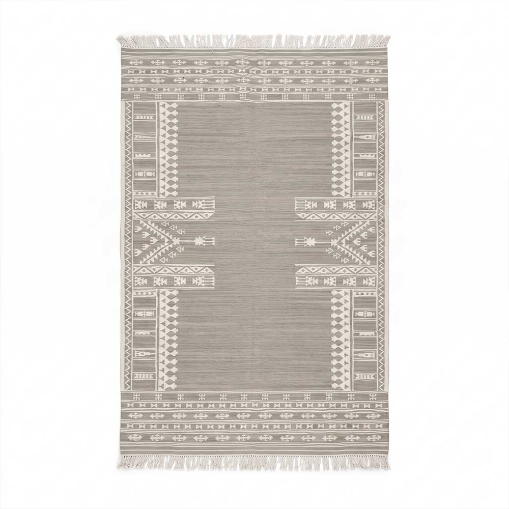 Top-down view of a rectangular Mirzapur handwoven rug featuring grey background and white bohemian geometric patterns with tasseled fringe.