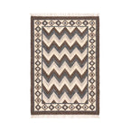 Handwoven Mirzapur wool area rug with charcoal and cream chevron pattern and tasseled fringe, overhead view.