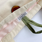 Close-up of a fabric item with ribbons and a label on a white background