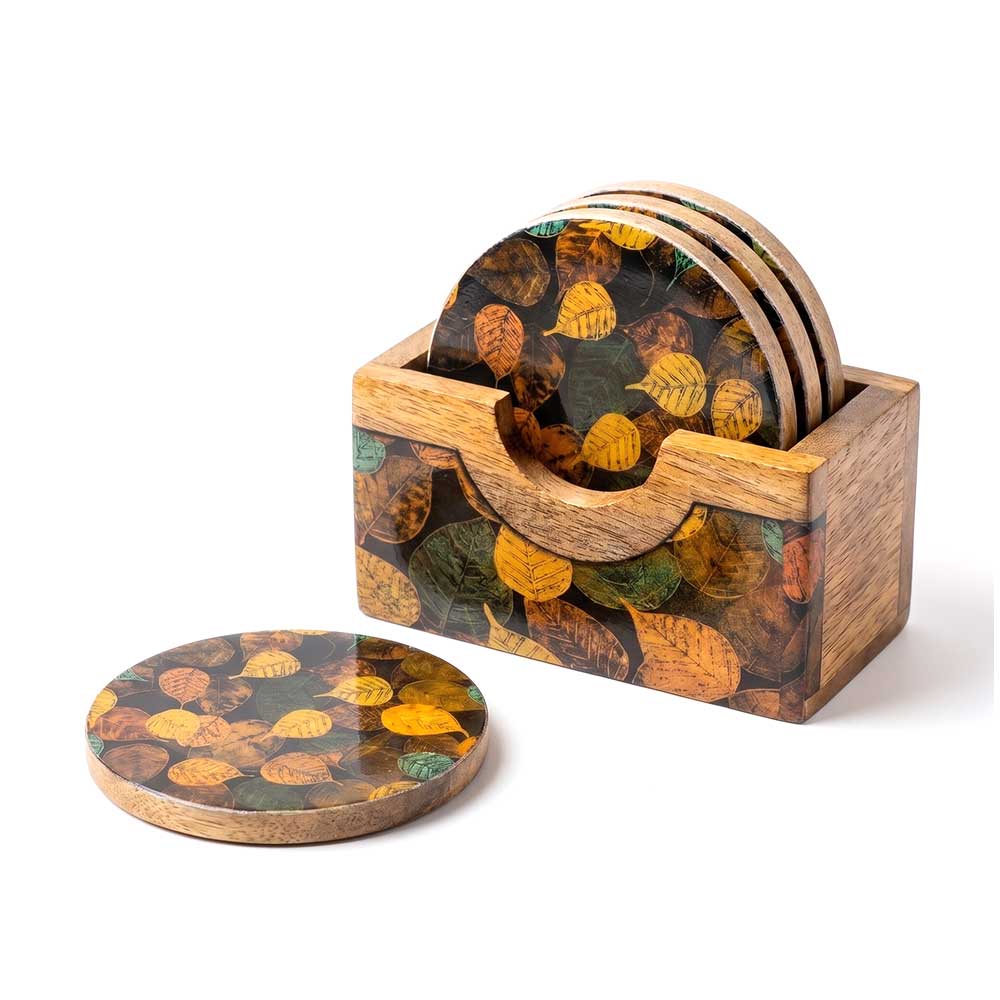 Close up view of the autumnal leaf enamel print on a round mango wood coaster.