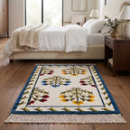 Mirzapur hand-tufted floral wool carpet styled in a cozy bedroom setting on hardwood floors at the foot of a bed.