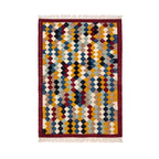 Flat-lay view of an authentic hand-woven Mirzapur geometric diamond rug with red border and tassels.