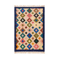 Full overhead view of a colorful hand-woven Mirzapur area rug with geometric diamond patterns and fringe edges.