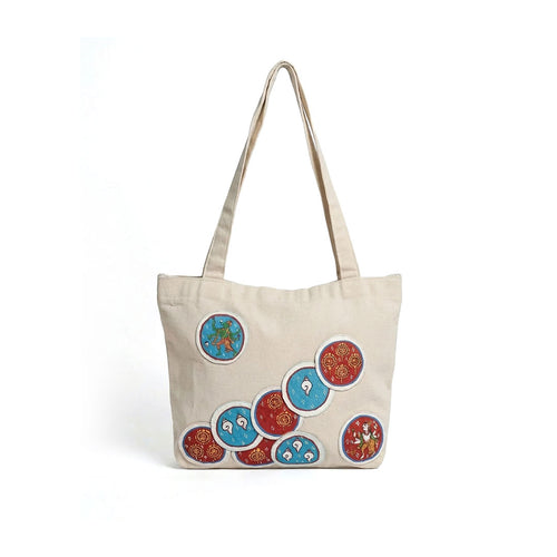 Beige tote bag with colorful circular patterns on a white background