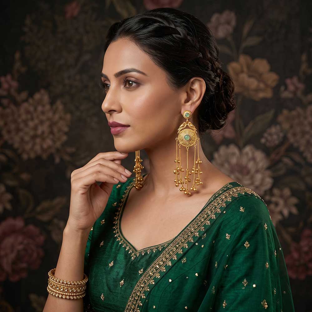 Close-up detail of the peacock carving and green stone inlay on the gold-plated Jhumka earrings.