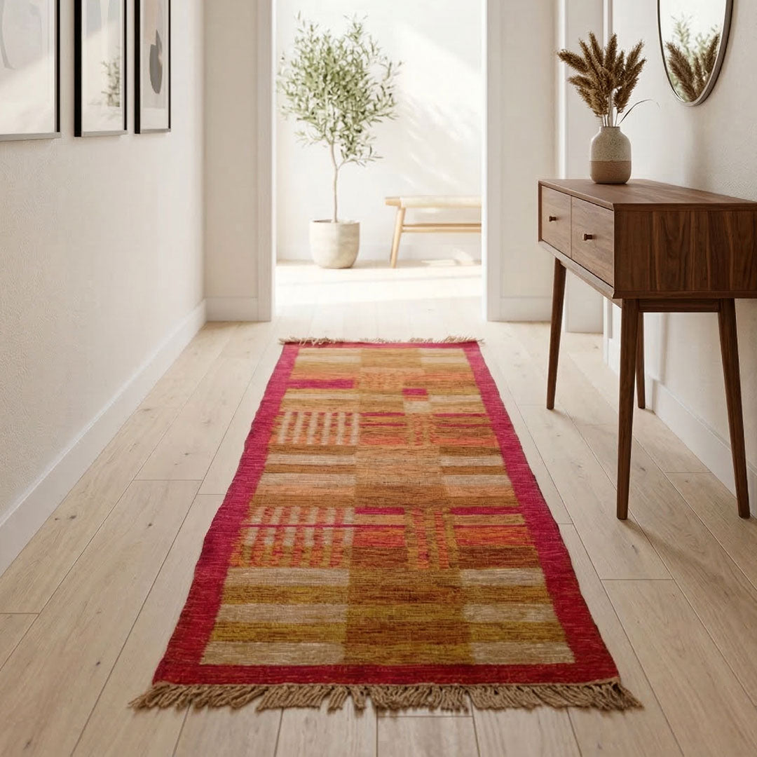 Colorful runner rug on a wooden floor with a wooden side table and plant in the background.