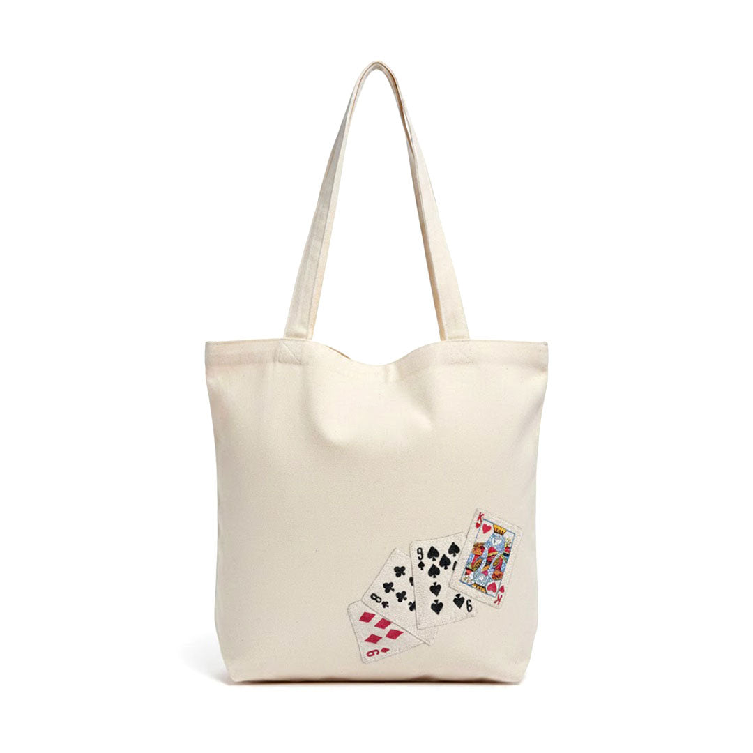 Beige tote bag with playing card designs on a white background
