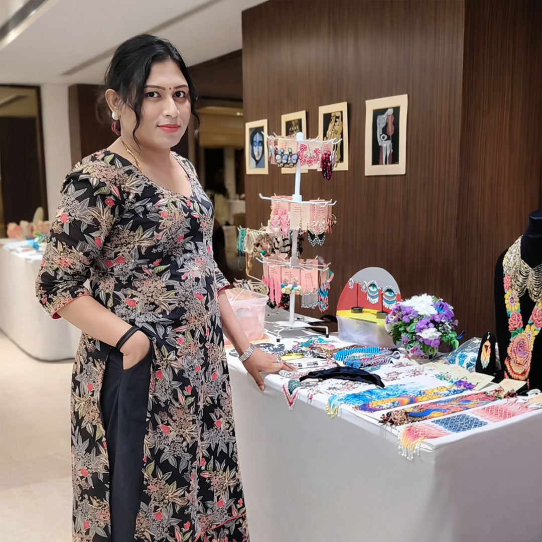 Woman standing next to a table with jewelry and decorative items in an indoor setting.