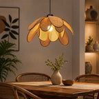 In-use lifestyle view of sugarcane petal pendant light hanging over a warm wooden dining table
