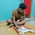 Artisan sitting on a wooden floor, working on a colorful craft project.