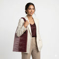 Woman holding a maroon handbag against a white background
